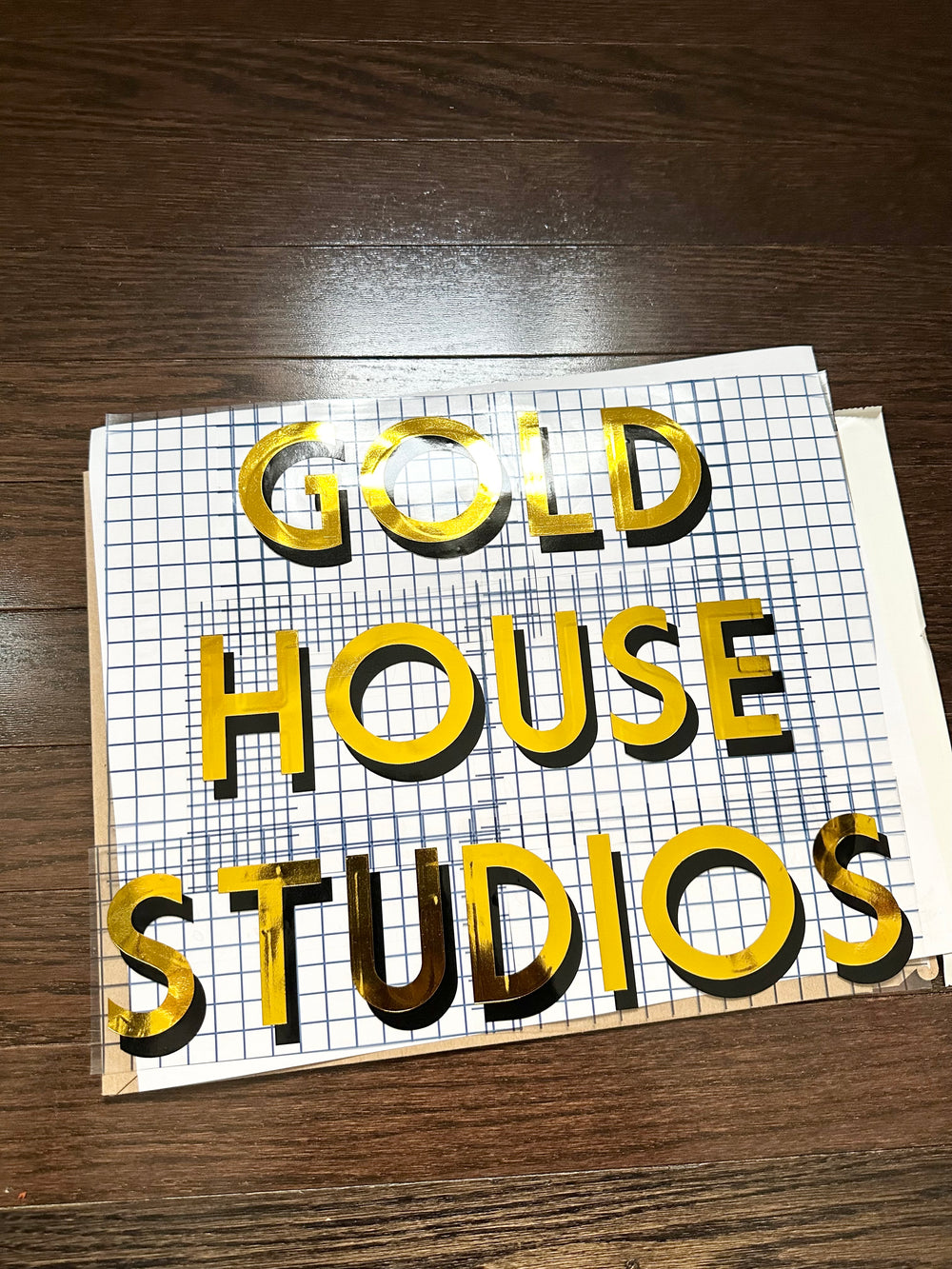 Gold and black Gold House Studios lettering on gridded tape