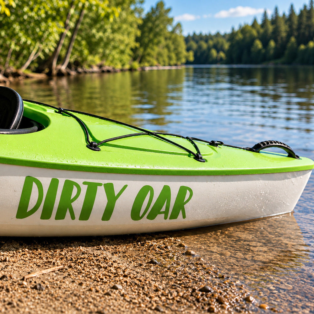 Green Dirty Oar lettering on a kayak beside a lake