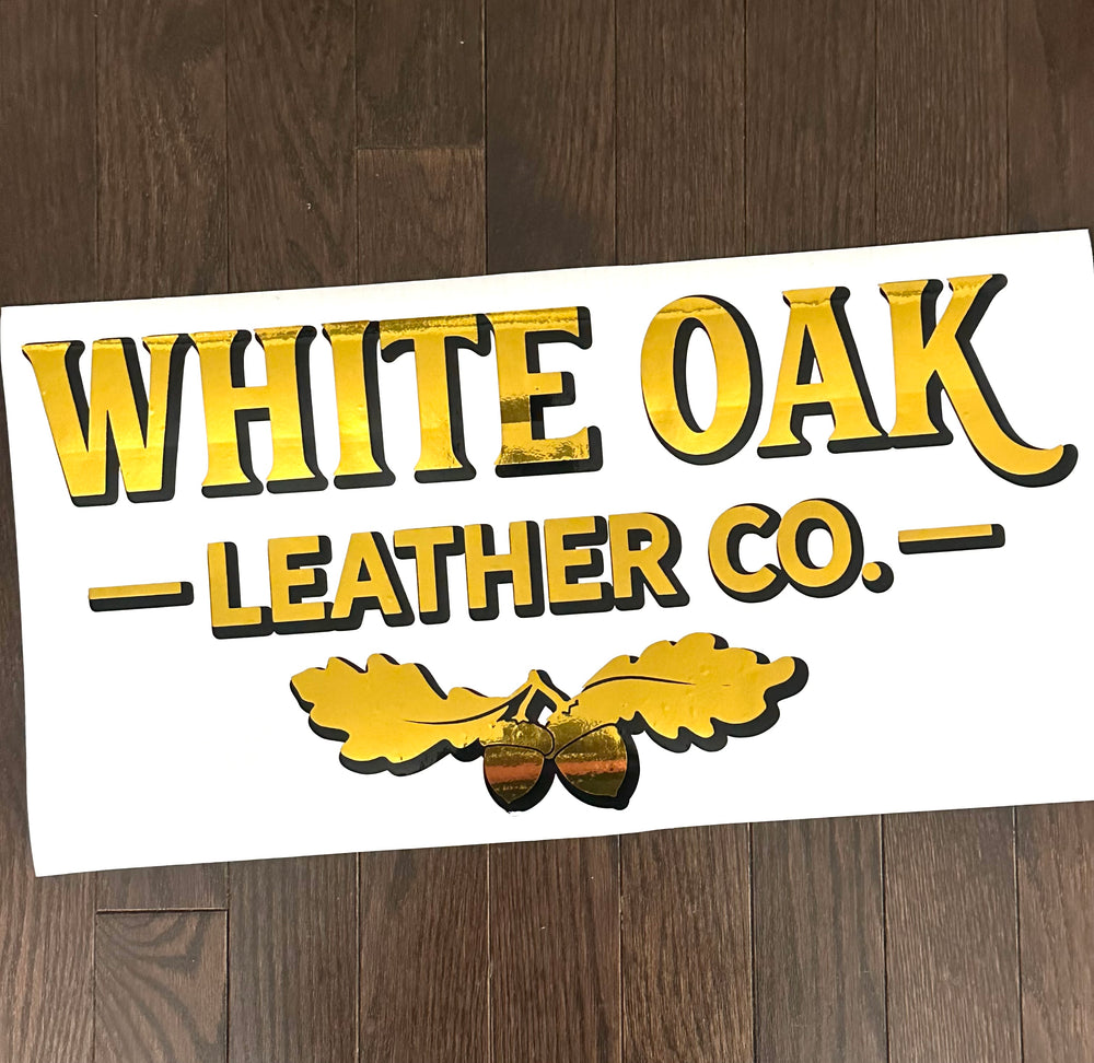 Gold and black White Oak Leather Co logo decal on backing