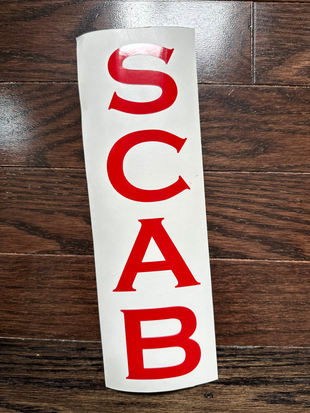 Red SCAB letters on curved backing
