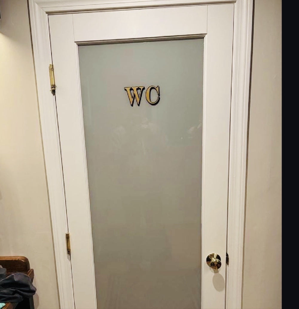 Customer photo: gold WC decal with black shadow on a frosted glass bathroom door