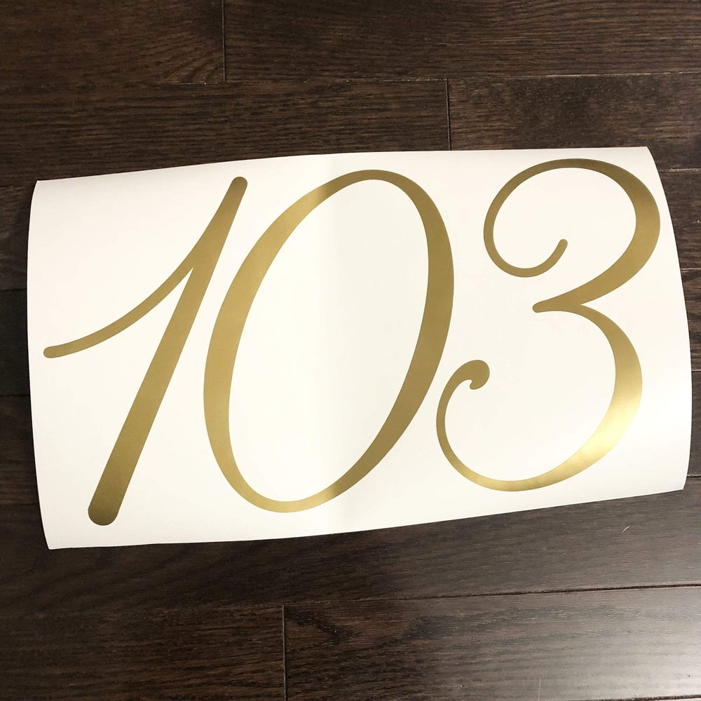 Gold-coloured 103 script numbers on backing