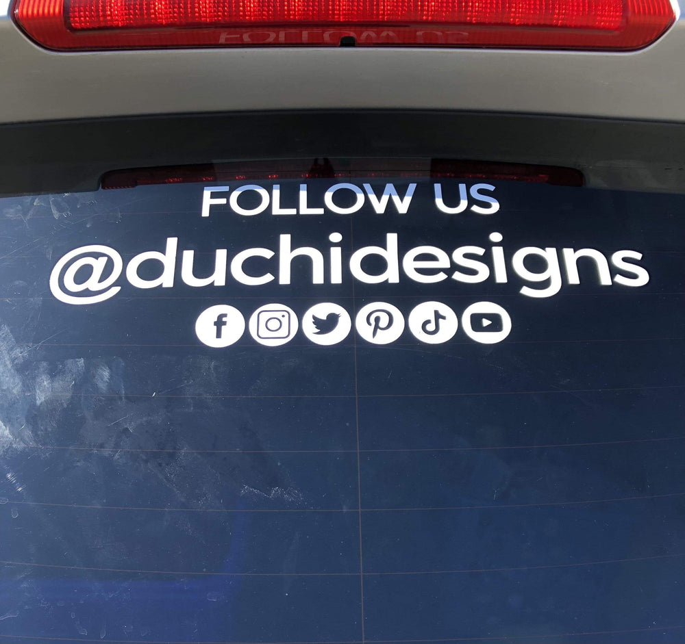 White @duchidesigns social lettering on a rear car window