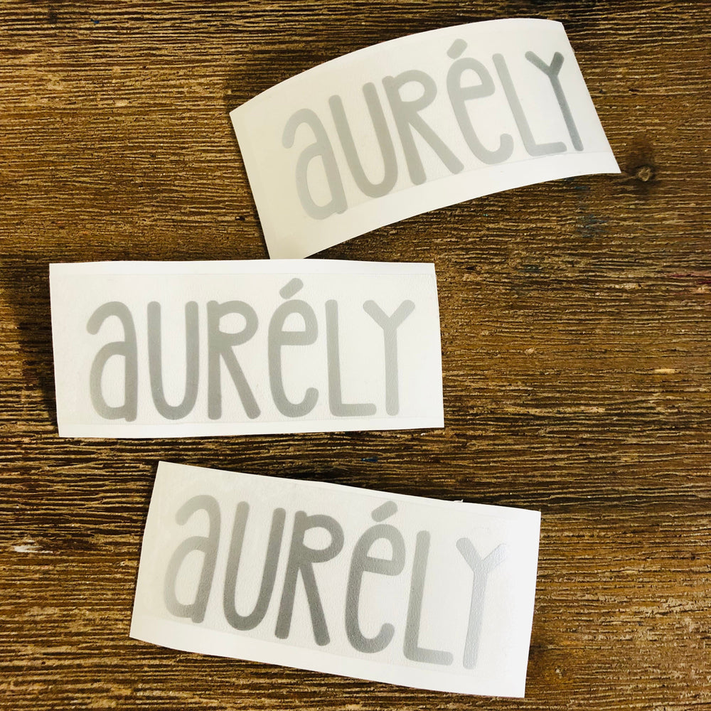 Three grey Aurély name decals on backing
