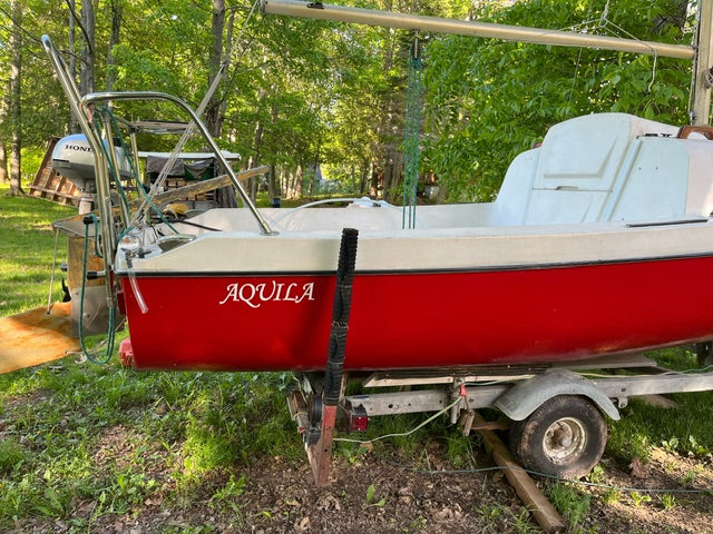 Aquila lettering on a red and white boat on a trailer