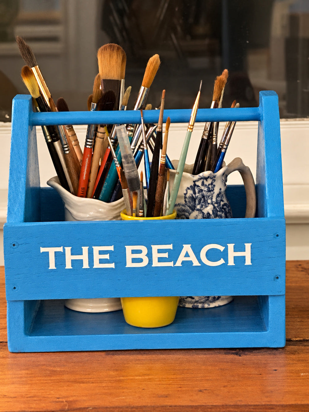 White THE BEACH lettering on a blue brush holder