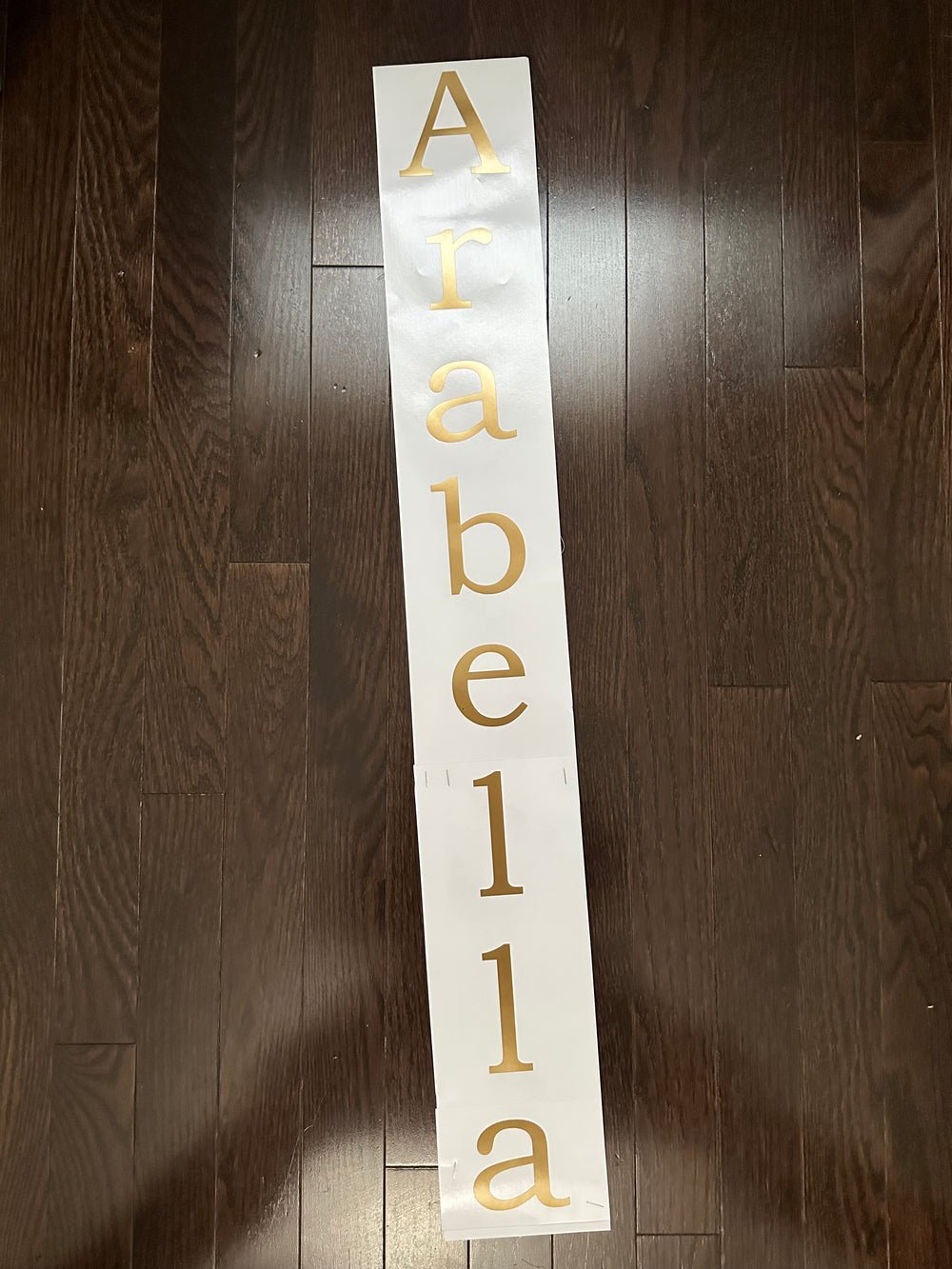 Gold-coloured Arabella name arranged vertically on backing