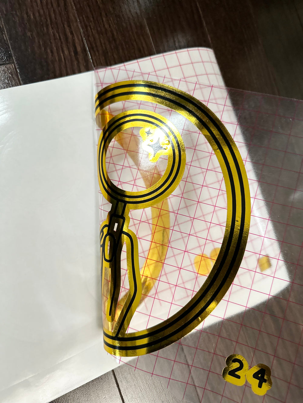 Close-up of gold and black circular logo under transfer tape