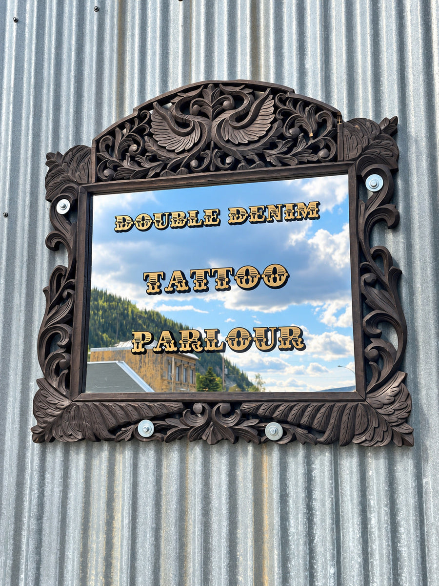 Gold Double Denim Tattoo Parlour lettering on an ornate mirror