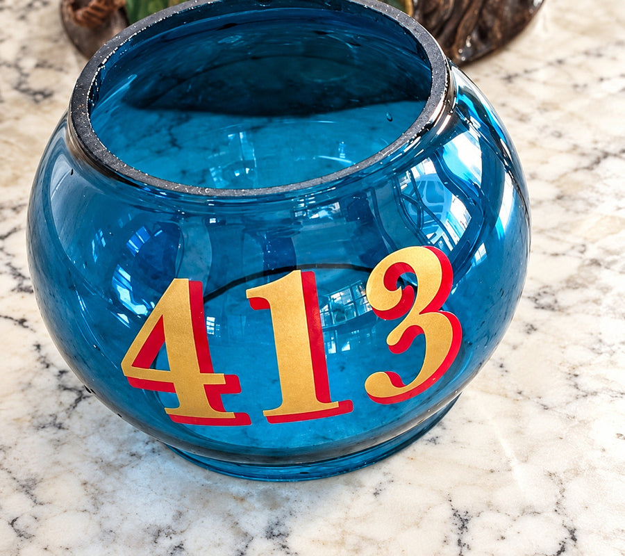 Gold and red 413 layered number lettering on a blue glass container