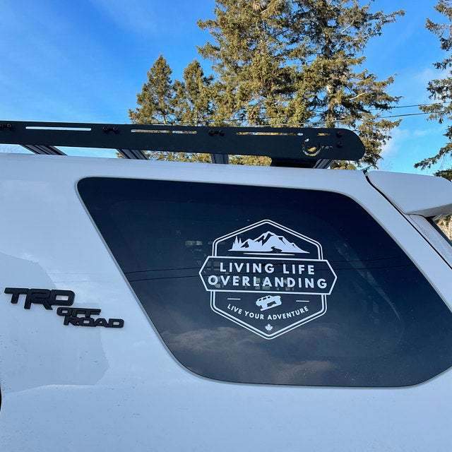 White Living Life Overlanding graphic on a vehicle window