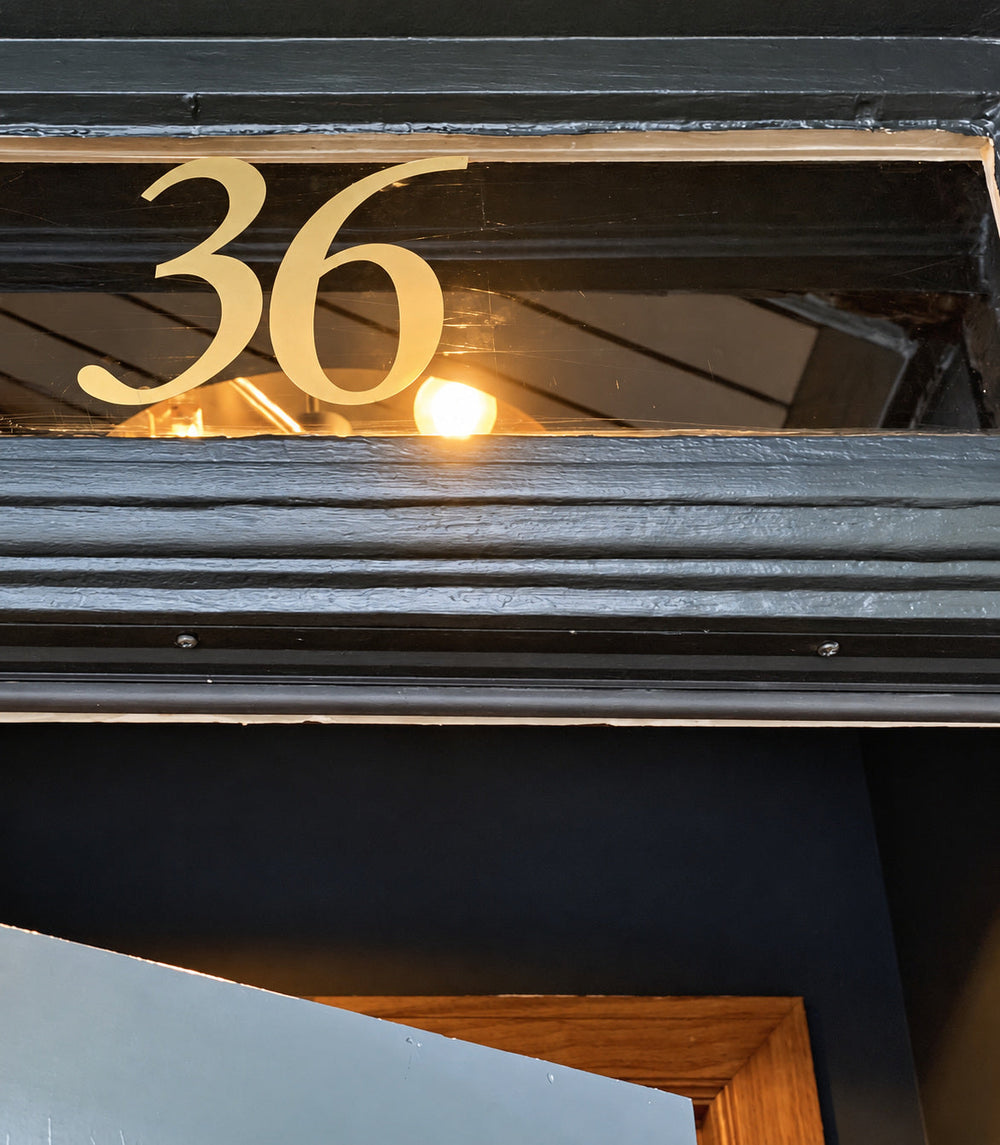 Gold-coloured 36 house numbers on narrow transom glass