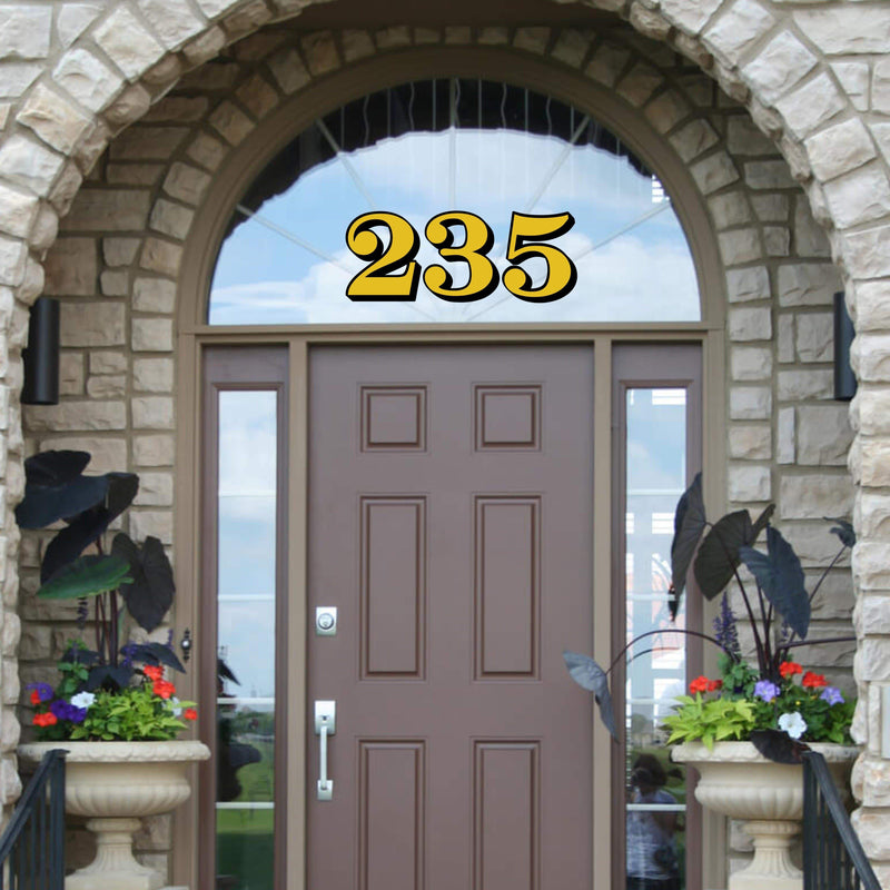 Gold and black 235 numbers on an arched transom above a brown door