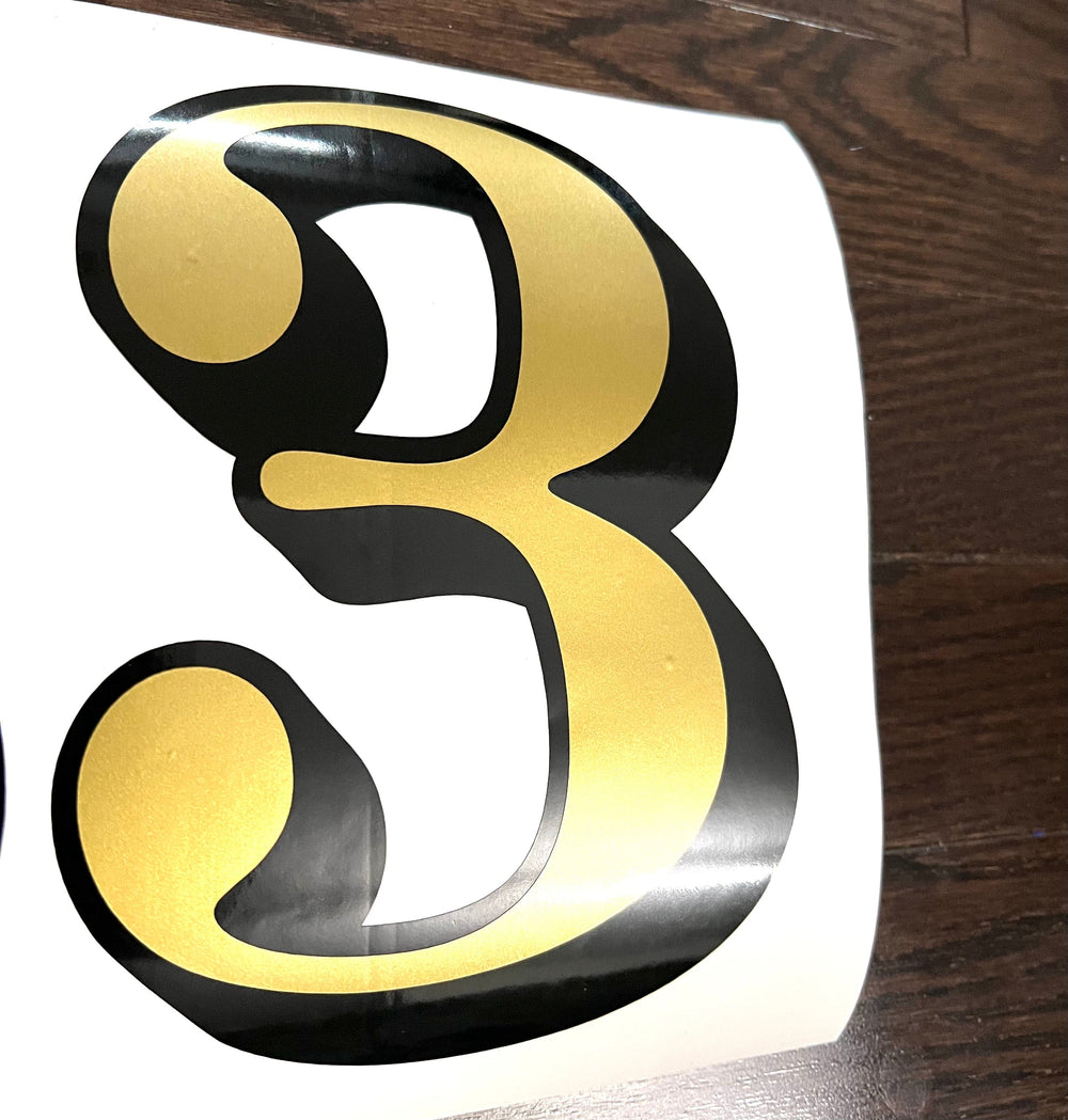 Gold and black digit 3 on white backing