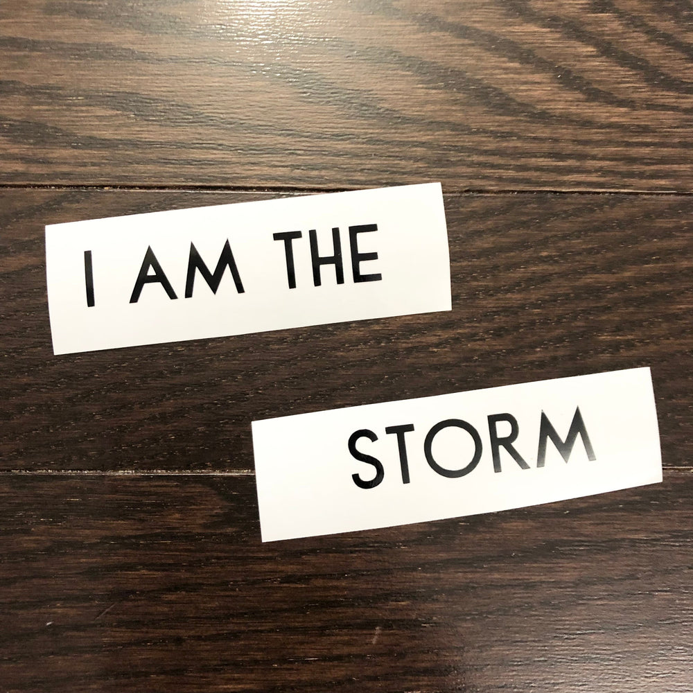 Black I am the Storm lettering on two backing strips