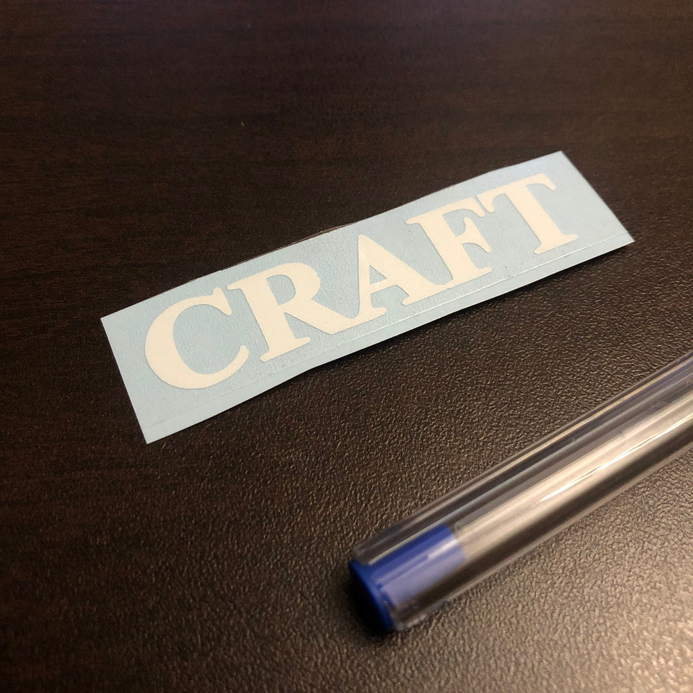 White CRAFT lettering on blue backing beside a pen
