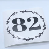 Black 82 numbers framed by a wreath on backing