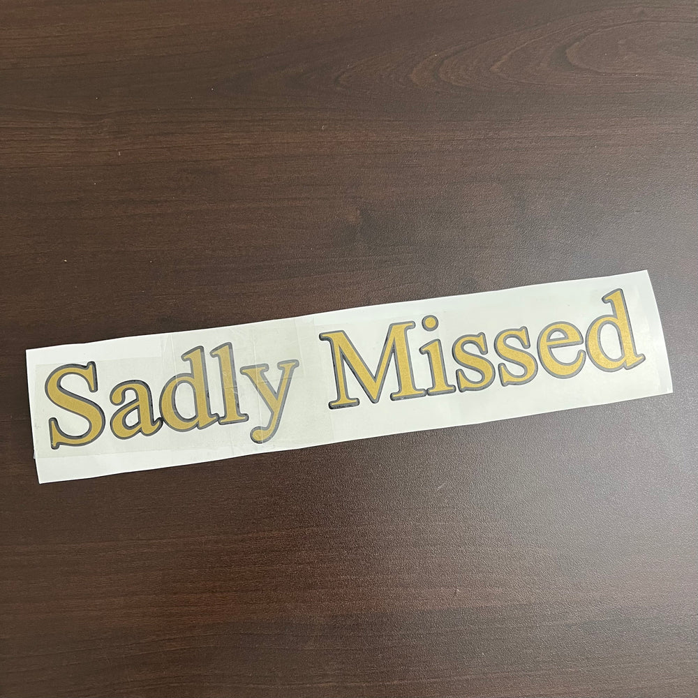 Gold-coloured Sadly Missed lettering decal