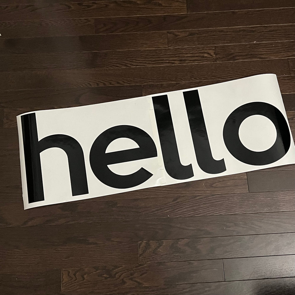 Black hello lettering decal on backing paper