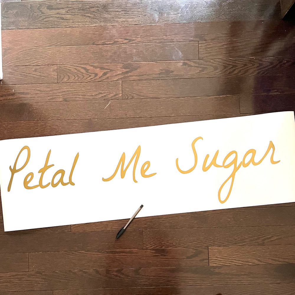 Gold-coloured Petal Me Sugar script decal on backing